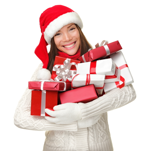 Christmas Shopping Woman Holding Many Christmas Gifts In Her Arms Wearing Santa Hat And Winter Clothing. Beautiful Young Female Model Isolated On White Background.