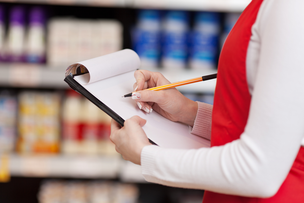 Saleswoman Writing On Clipboard In Grocery Store